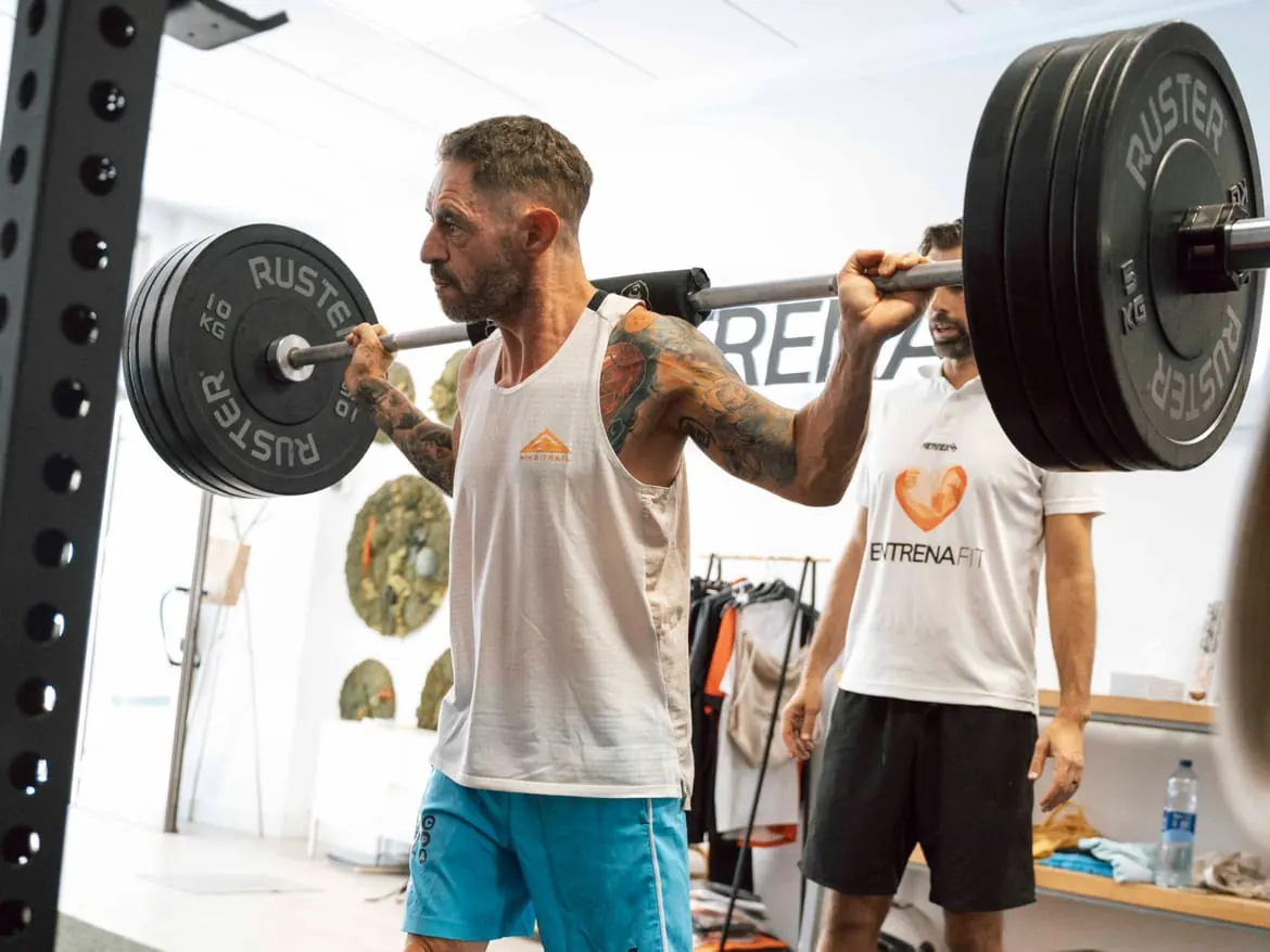 Entrenador personal supervisando una sentadilla con barra en Entrenafit, cerca de Fuengirola